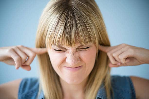 Jeune femme qui se bouche les oreilles pour se protéger des nuisances sonores et du bruit